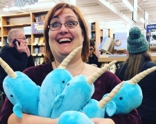 Lady holding a bunch of stuffed narwhals