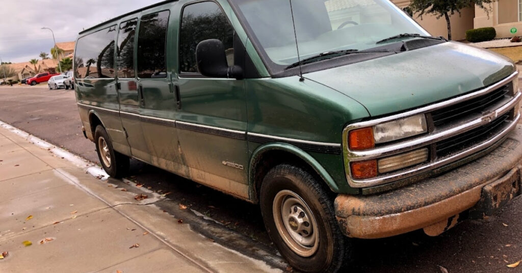 A very muddy green cargo van