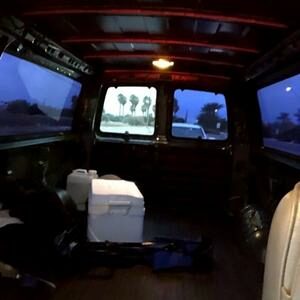 The inside of a cargo van with a cooler and other misc camping gear