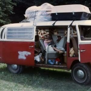 Old VW bus, packed with small children inside and camping gear on top